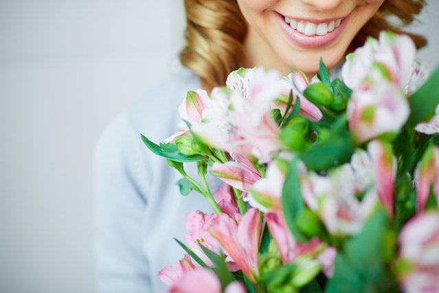 Femme qui reçoit un bouquet suite à une livraison de fleurs